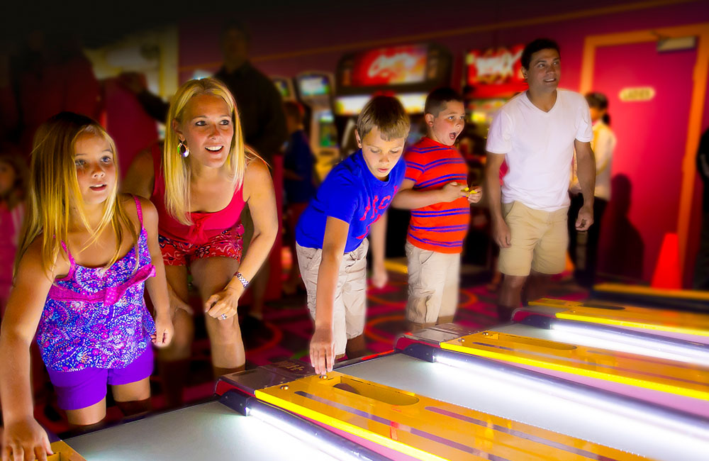 Adults and children enjoying a game of skeet-ball in the arcade at Calypso's.