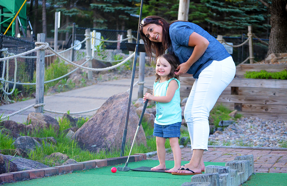 Two guests enjoying a round of mini-golf on the miniature golf course at Calypso's Cove.