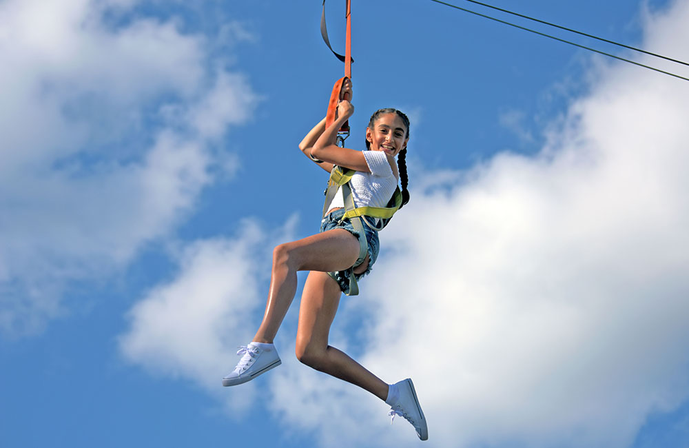 Young girl smiling while taking a ride on the zipline at Calypso's Cove.